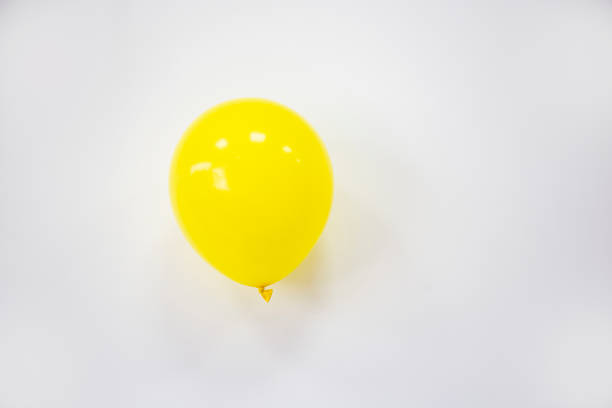 closeup of an inflated yellow heart-shaped balloon with a smile drawn in it on a yellow background, to depict happiness