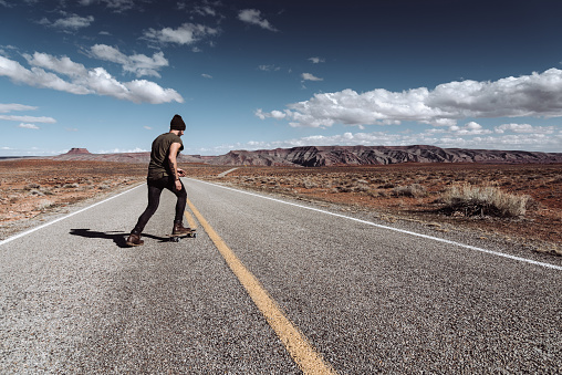 man using the skateboard in the monument valley