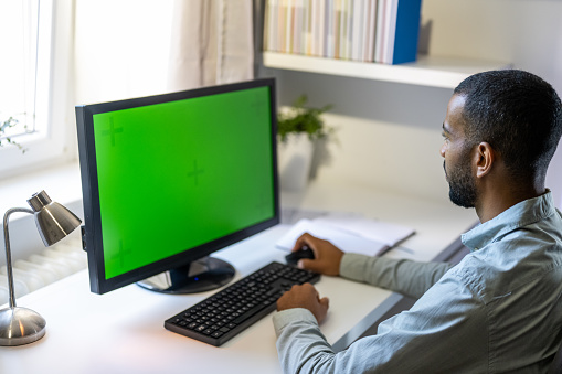 Multiracial young male remote worker using computer with chroma key green screen in home office