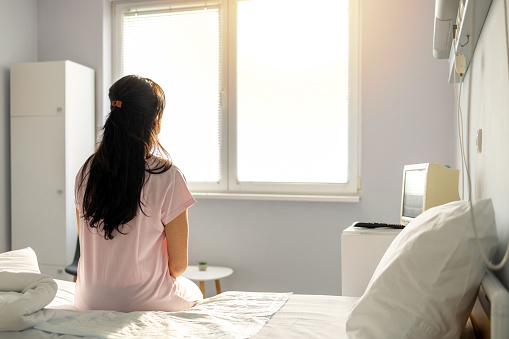 Female patient in hospital gown waits for test results