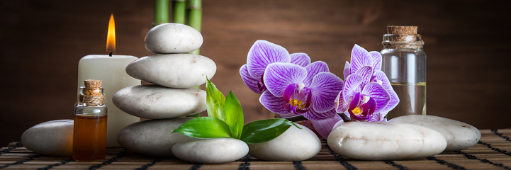 Massage oil ,white zen balance stones,orchid and bamboo leaves on the wooden table