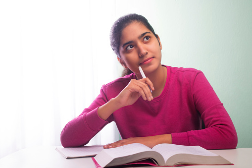 young happy teenager girl thinking and writing in notebook