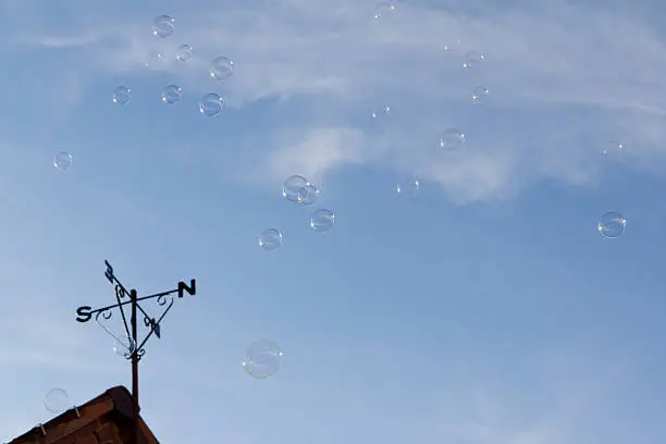 Floating in the air-bubbles transparent and delicate float free, not following the directions of the weather vane left below them.