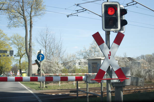red light of the railway crossing and lowered barrier blocking the passage - railroad crossing railway signal gate nobody imagens e fotografias de stock