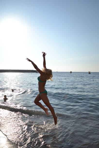 woman jumping in the sea at sunset