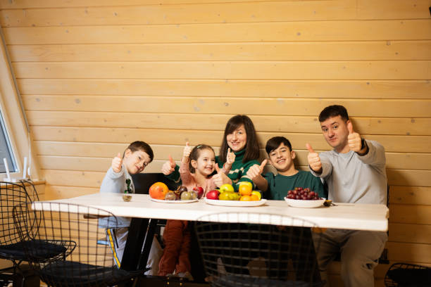 family with three kids eat fruits in wooden country house on weekend and shows thumb up. - boy and girl in kitchen thumbs up bildbanksfoton och bilder