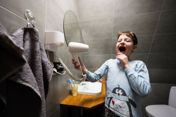 istock Boy singing with a hair dryer at bathroom. 1479670940