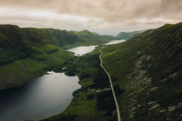 vista aérea da estrada ao longo da terra cênica dos lagos em colinas verdes na noruega - more objects - fotografias e filmes do acervo