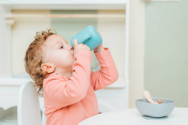 istock Little child drinking water from a plastic cup at home 1479674423