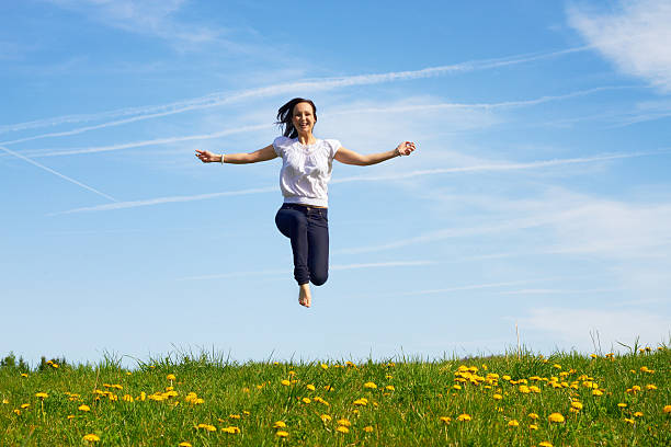 smiling girl jumping against blue sky stock photo