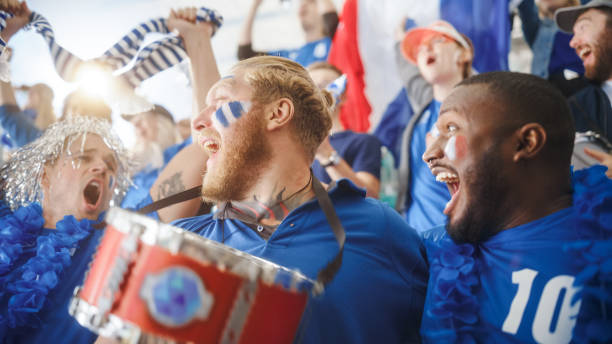 istock Sport Stadium Big Event: Three Diverse Fans with Painted Faces Cheering, Beating the Drum, Laughing, Having Fun, Shout for Soccer Team to Win. People Celebrate Scoring a Goal, Championship Victory 1479681344