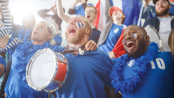 istock Sport Stadium Big Event: Three Diverse Fans with Painted Faces Cheering, Beating the Drum, Laughing, Having Fun, Shout for Soccer Team to Win. People Celebrate Scoring a Goal, Championship Victory 1479681423