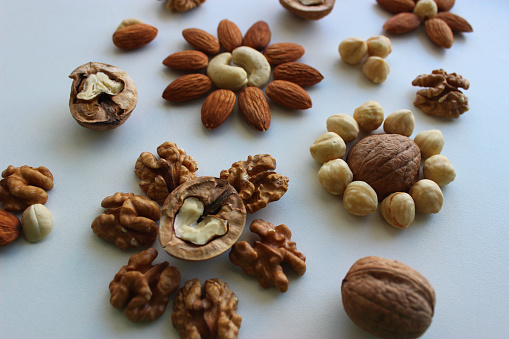 Different Types Of Nuts In Form Of Flowers On White Surface Isolated
