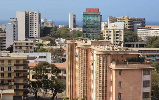 Dakar (Plateau), Senegal:  Maginot building (Credit Foncier), built in 1950, was the first modern high-rise building in the city, with telephones, garbage disposal and elevators. Corner of Avenue de la République and Avenue Maginot (now Av. Lamine Guèye). Also in the image the glass clad Rivonia building, the modernist façade of the Senegalese Parliament and the colonial St Joan of Arc Institution - Atlantic Ocean in the background.