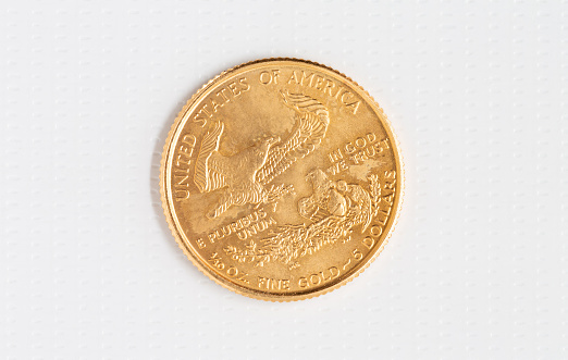 Back side of a fine gold American coin with a flying eagle on white background.