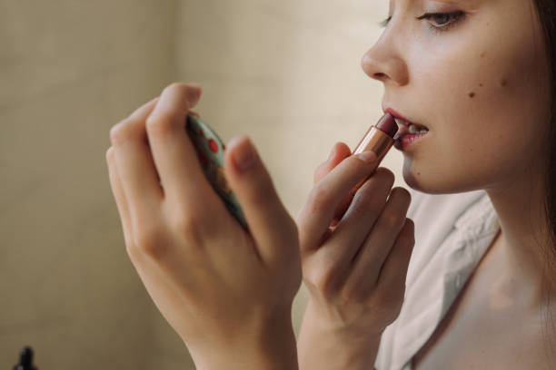 istock Woman applying pink lipstick and looking in mirror 1479686202