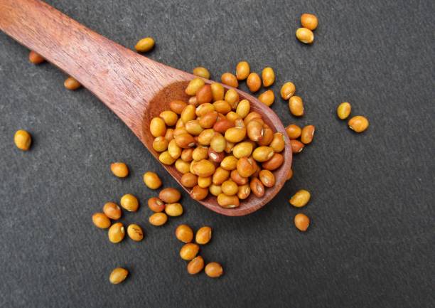 semillas de guisante de paloma en una cuchara de madera sobre fondo negro vista superior - pigeon pea” fotografías e imágenes de stock