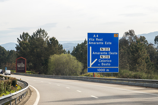 Image of section of the A4 motorway, transmontana motorway, Porto, Vila Real, Portugal. Blue vertical information board, directions. Beautiful day with high clouds.