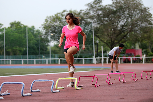 An Asian young woman is focusing on routine athletic training in stadium