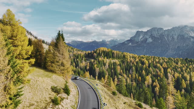 Aerial view of car on  winding road through Alps in autumn