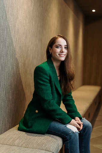 A young latin female financial advisor sitting and smiling at the camera.