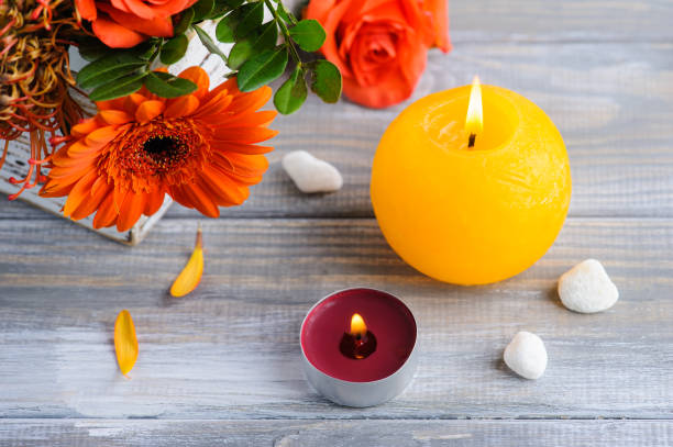 istock Flat lay still life with orange flowers, lit candles and pebbles 1479689913