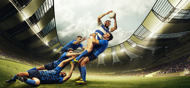 Deporte profesional. Hombres, jugadores de rugby durante el juego, atrapando pelota en un estadio al aire libre 3D. Audiencia borrosa en el fondo. Emociones photo