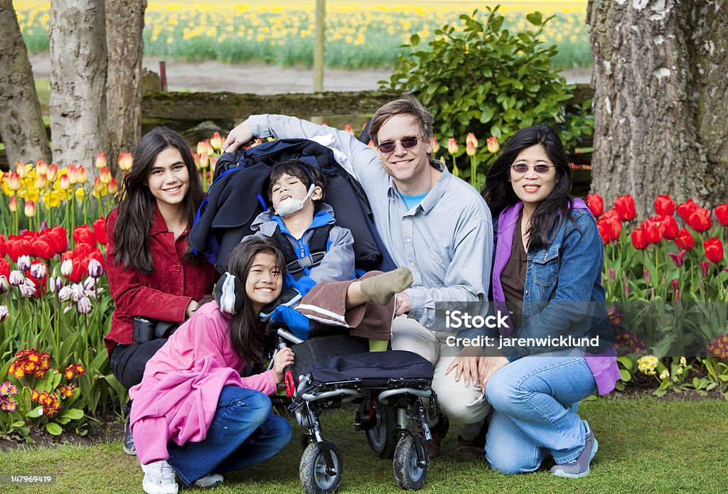 Família com garoto com deficiência no jardins de tulipas - Foto de stock de Família royalty-free