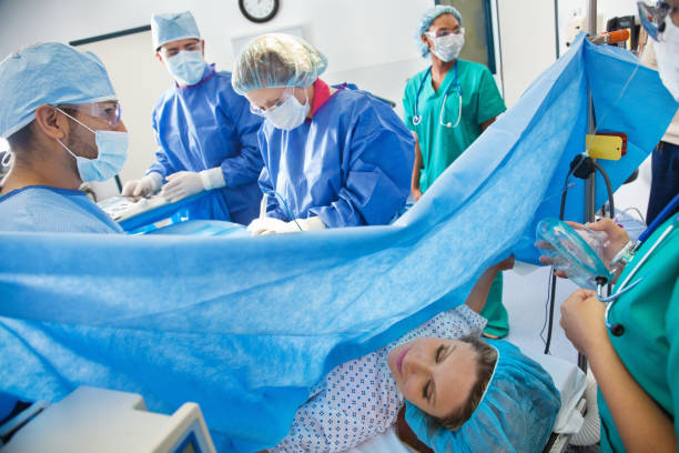 Surgical team performing Caesarean section on pregnant woman Surgical team performing Caesarean section on pregnant woman.   pregnancy and childbirth stock pictures, royalty-free photos & images