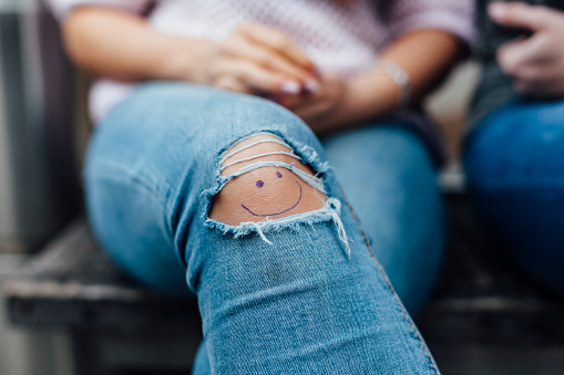 Teen with smiley on knee in close up