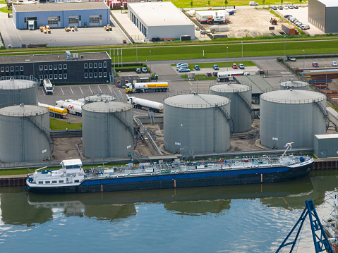 Container freight ship at a fuel terminal in the port of Kampen, Overijssel, Netherlands in an industrial aeria seen from above.