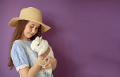 schoolgirl girl holding a white rabbit in her hands on a purple background