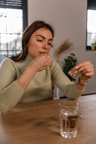 istock Young woman reading a label on a pill packet while taking her medication 1479707996