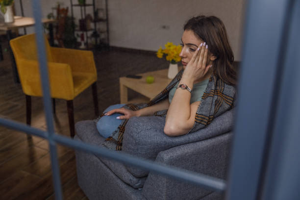 istock Young woman sitting on the sofa, wrapped in a blanket, contemplating life's problems 1479708234