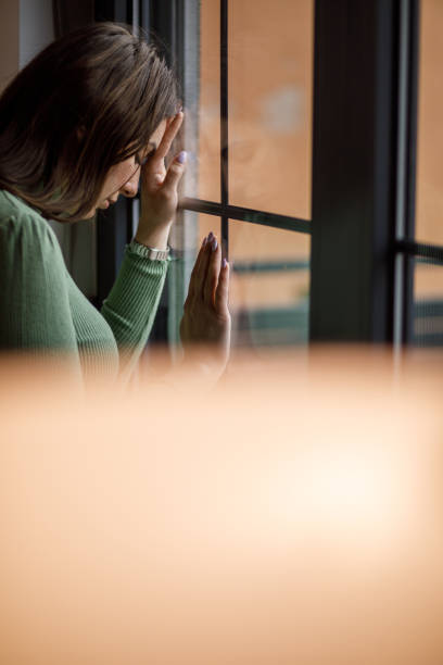 istock Anxious young woman standing by the window, struggling with negative emotions 1479708838