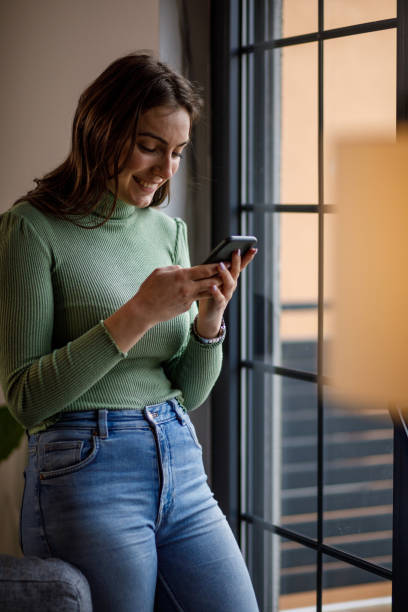istock Young woman smiling while responding to a text message via smart phone 1479708984