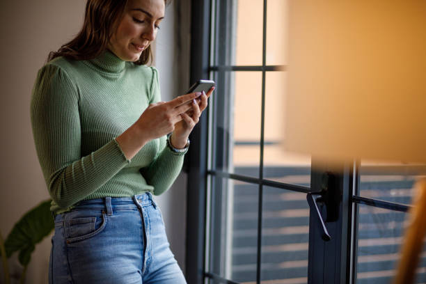 istock Young woman smiling while responding to a text message via smart phone 1479708989