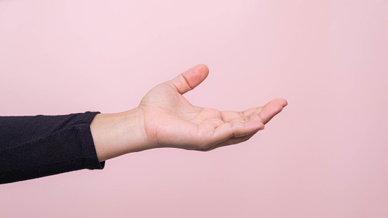 Close up of woman's hand reaching out ready to help or receive, isolated on pink background. Helping hand outstretched for salvation.
