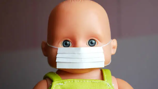 Close-up of the face of a baby doll with a protective face mask