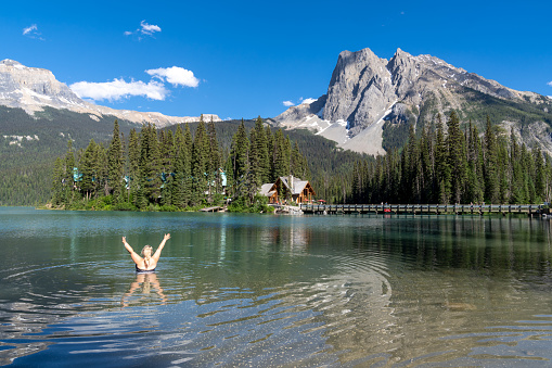 Happy blonde woman swims in Emerald Lake in Yoho National Park, British Columbia on a sunny summer day