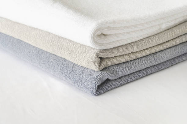istock three folded clean terry towels on white background. stack of towels in pastel colors on bedsheet 1479724234