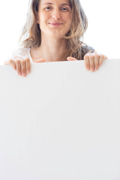 Woman is holding blank page and is looking at camera.