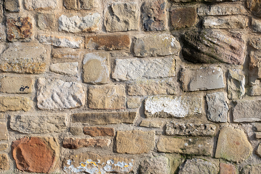 A background or texture of a grey stone masonry wall used as siding of a house. 