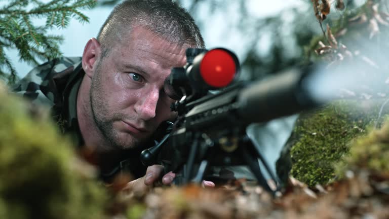 SLO MO LD Male sniper shooting his rifle while looking through the scope