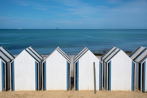 Yport, beach huts by the sea. Emergence of the Fécamp offshore wind farm in the background