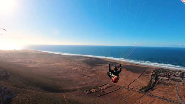 Freedom paragliding flying over dry country in African Morocco ocean coast in sunny summer, Adrenaline Adventure Sport