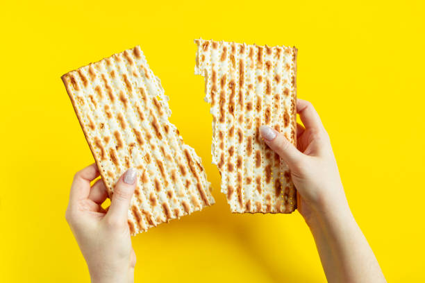la mujer sostiene matzá. celebrando la tradicional fiesta judía de pascua o pésaj. matzá sobre fondo amarillo. - passover matzo bread breaking fotografías e imágenes de stock