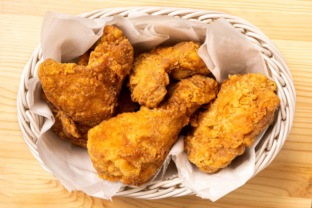 istock Crispy fried chicken pieces in a white woven basket on light wood from above. 1479727612