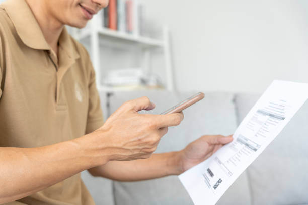 man use phone to scan barcode or QR codes to pay credit card bill after receiving document invoice online. payment, receive, paying electricity, digital payments without money, technology, scanning el hombre usa el teléfono para escanear códigos de barras o códigos qr para pagar la factura de la tarjeta de crédito después de recibir la factura del documento en línea. pago, recibir, pagar electricidad, pagos digitales sin dinero, tecnología, es
