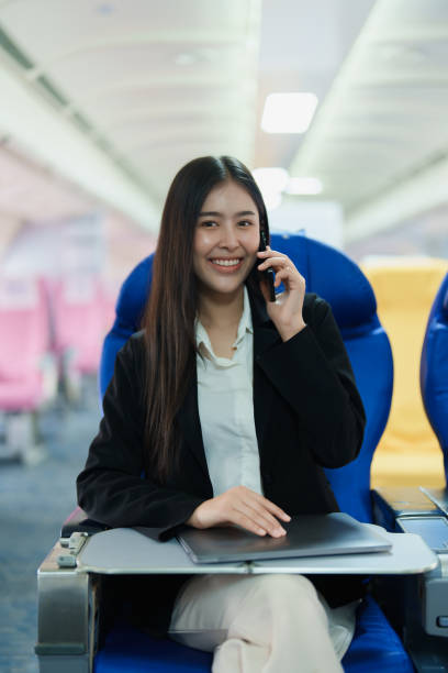 istock Asian business woman passenger sitting on business class luxury plane while working using smartphone mobile talking and use laptop computer with simulated space using on board wireless connection 1479732055